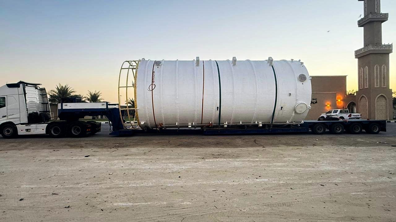 Large process tank on a lowbed trailer at sunset