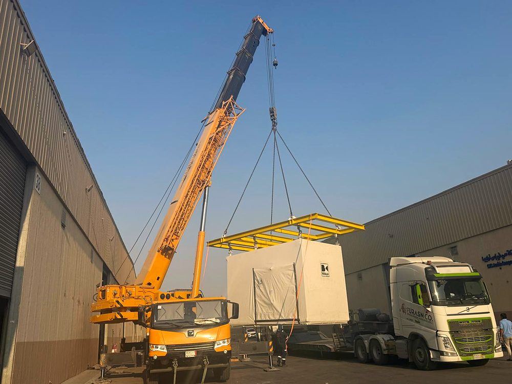 Mobile crane lifting a module onto a truck